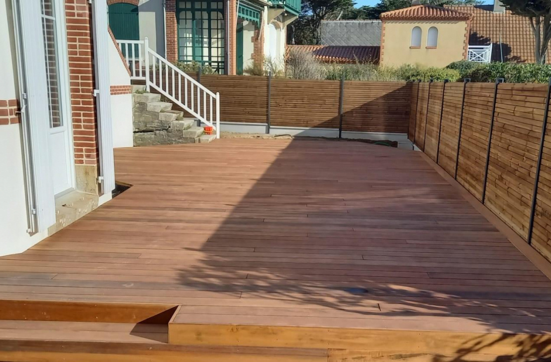 Cl&ocirc;tures en bois clair en ad&eacute;quation avec une terrasse en bois plus fonc&eacute;