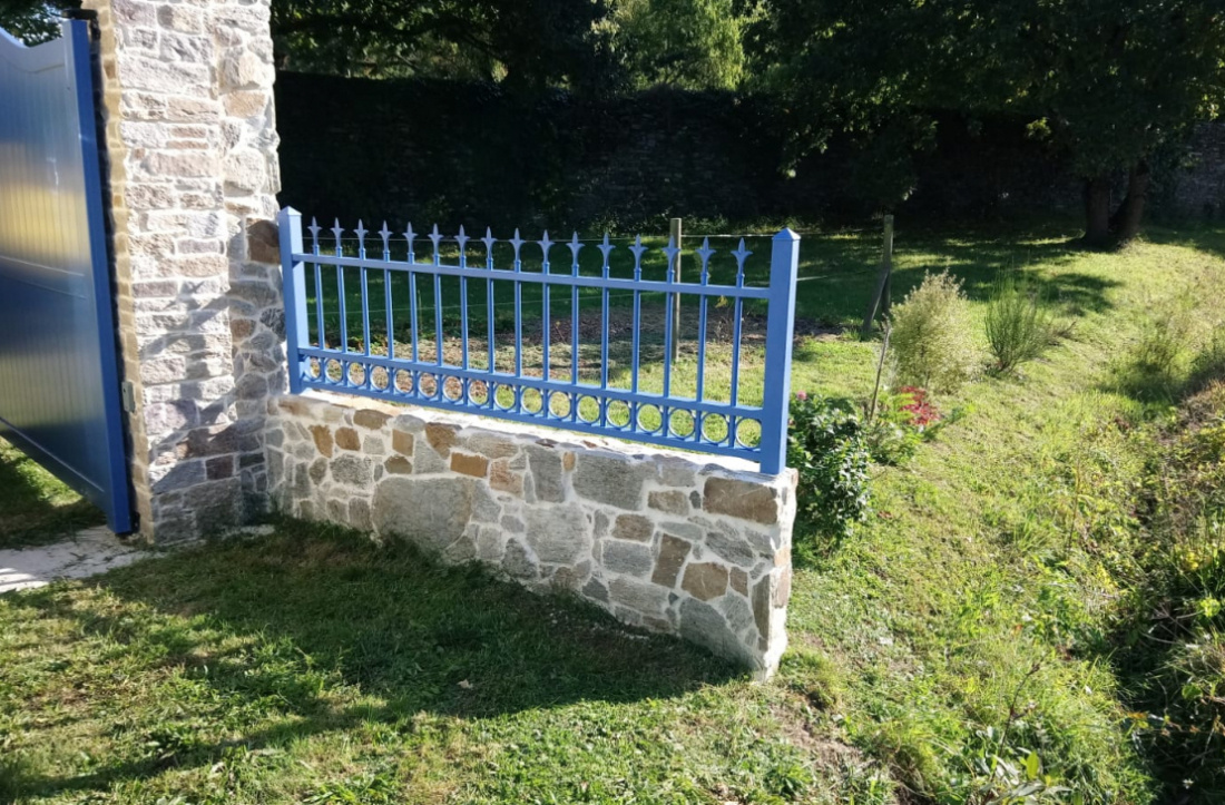 Cl&ocirc;tures en fer forg&eacute; bleue sur muret en pierre